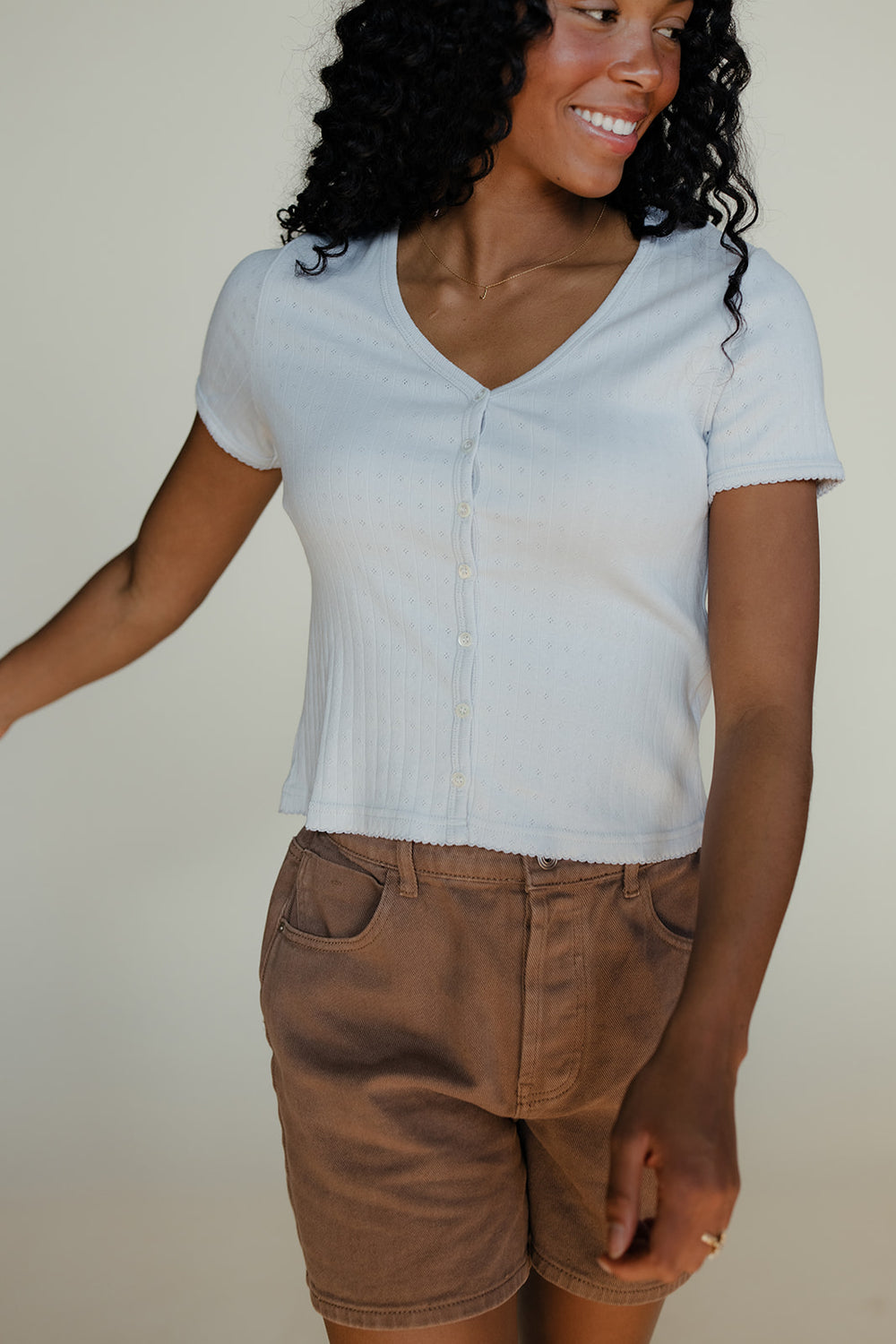Woman wearing a blue tee and brown shorts on a white background