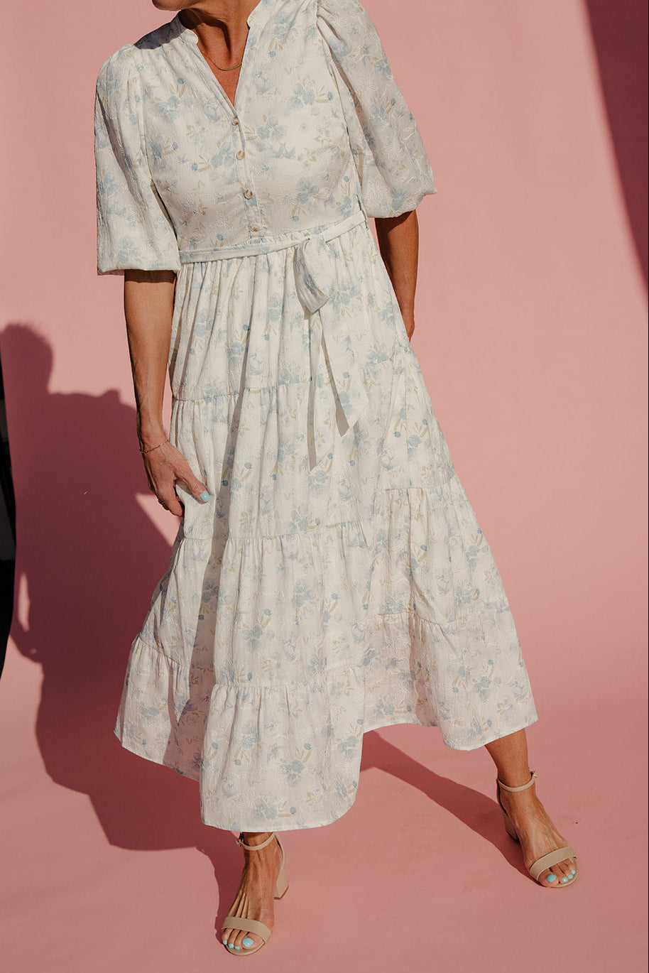 Woman wearing a light-colored floral dress against a pink background