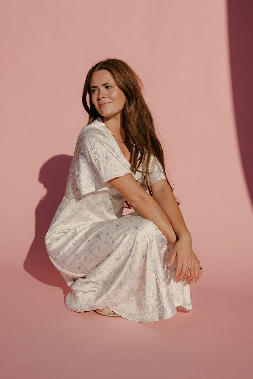 Woman in a white dress sitting on a pink background