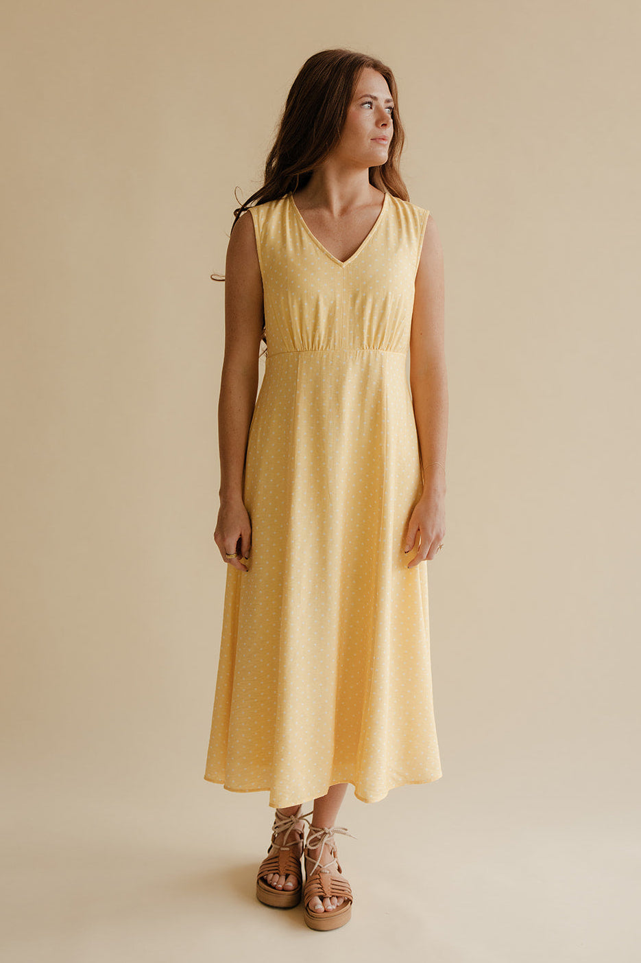 Woman wearing a yellow dress against a beige background