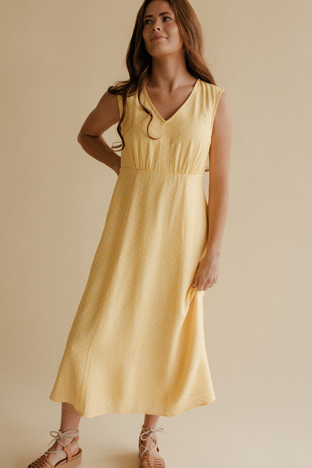 Woman wearing a yellow dress against a beige background