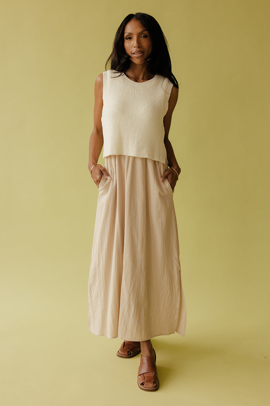 Woman wearing a white sleeveless top and beige skirt against a yellow background