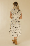 Woman wearing a polka dot dress with a beige background