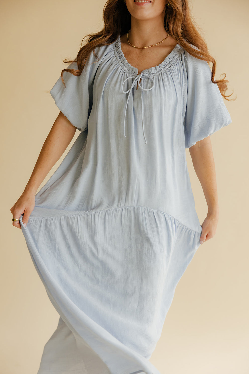 Woman wearing a light blue dress with a beige background