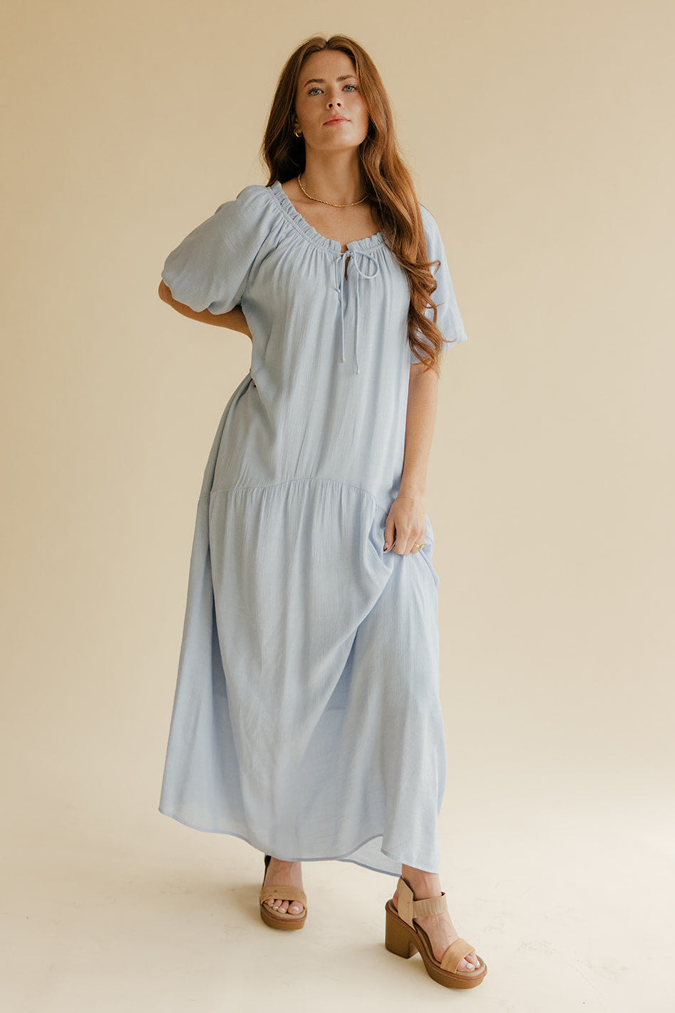 Woman wearing a light blue dress against a beige background
