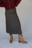 Person wearing a red shirt, plaid skirt, and brown boots on a plain background