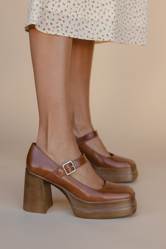 Brown platform shoes with a buckle on a neutral background