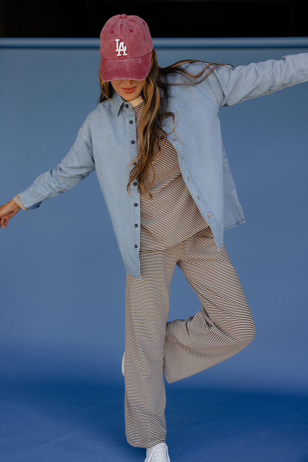 Person wearing a light blue shirt, striped pants, and a red cap with 'LA' on a blue background