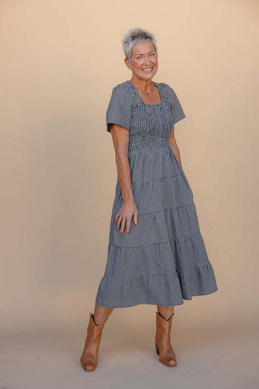 Woman wearing a blue checkered dress against a beige background