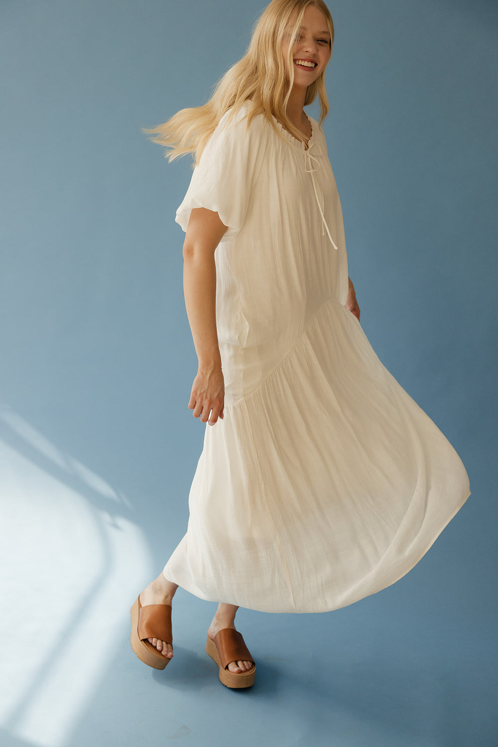 Woman wearing a flowing white dress against a blue background