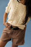 Woman wearing a cable knit sweater and brown shorts