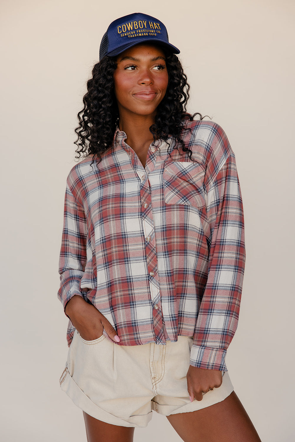 Person wearing a plaid shirt and cowboy hat against a plain background