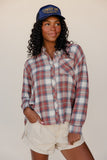 Person wearing a plaid shirt and cowboy hat against a plain background