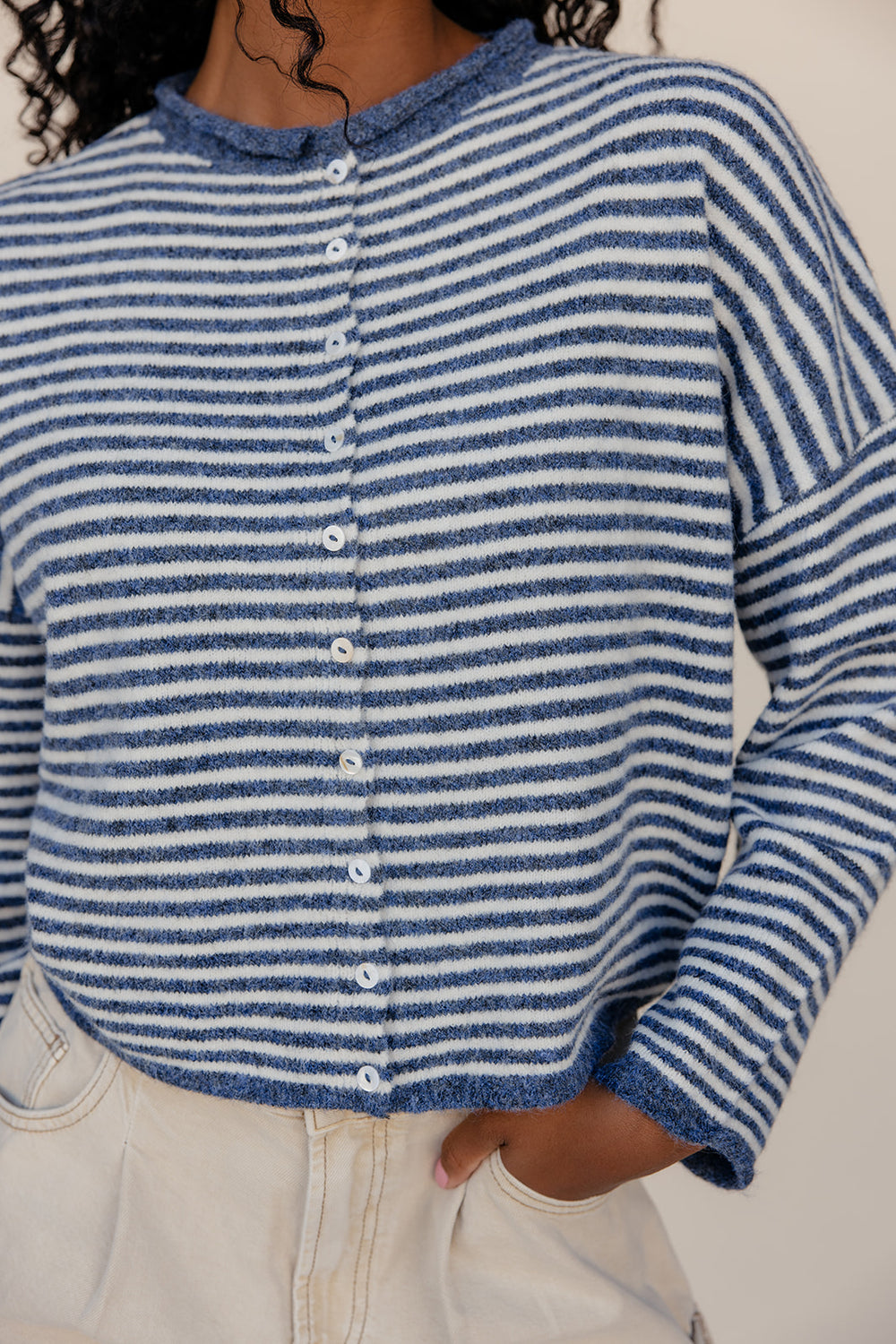Blue and white striped cardigan worn by a person on a neutral background