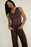 Woman wearing a brown sleeveless top and pants against a plain background