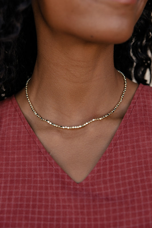 Close-up of a person wearing a gold necklace with a red garment.