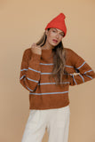 Woman wearing a brown striped sweater and red beanie against a beige background