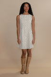 Woman wearing a polka dot dress with beige boots on a beige background