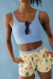 Person wearing a blue crop top and patterned shorts against a light blue background
