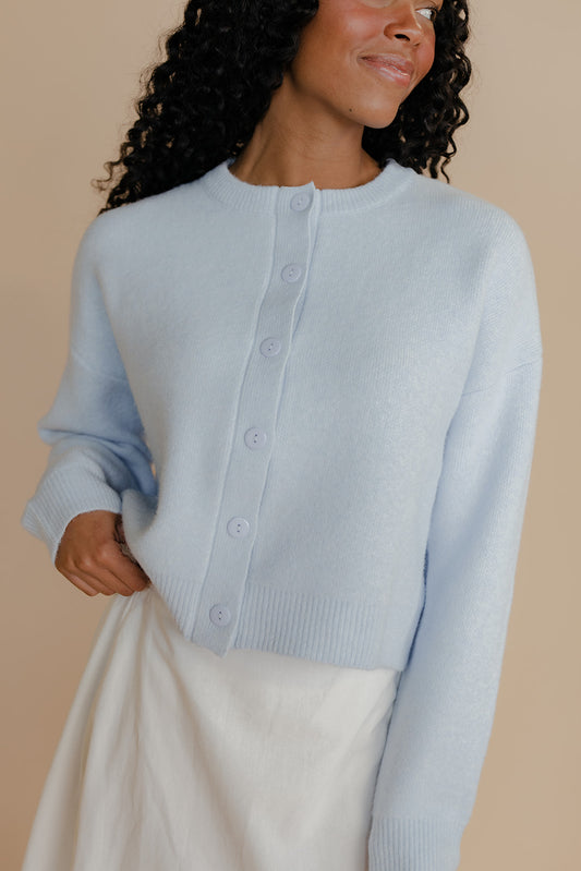 Woman wearing a light blue cardigan against a beige background