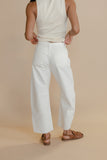 Person wearing a white tank top and wide-leg pants on a beige background