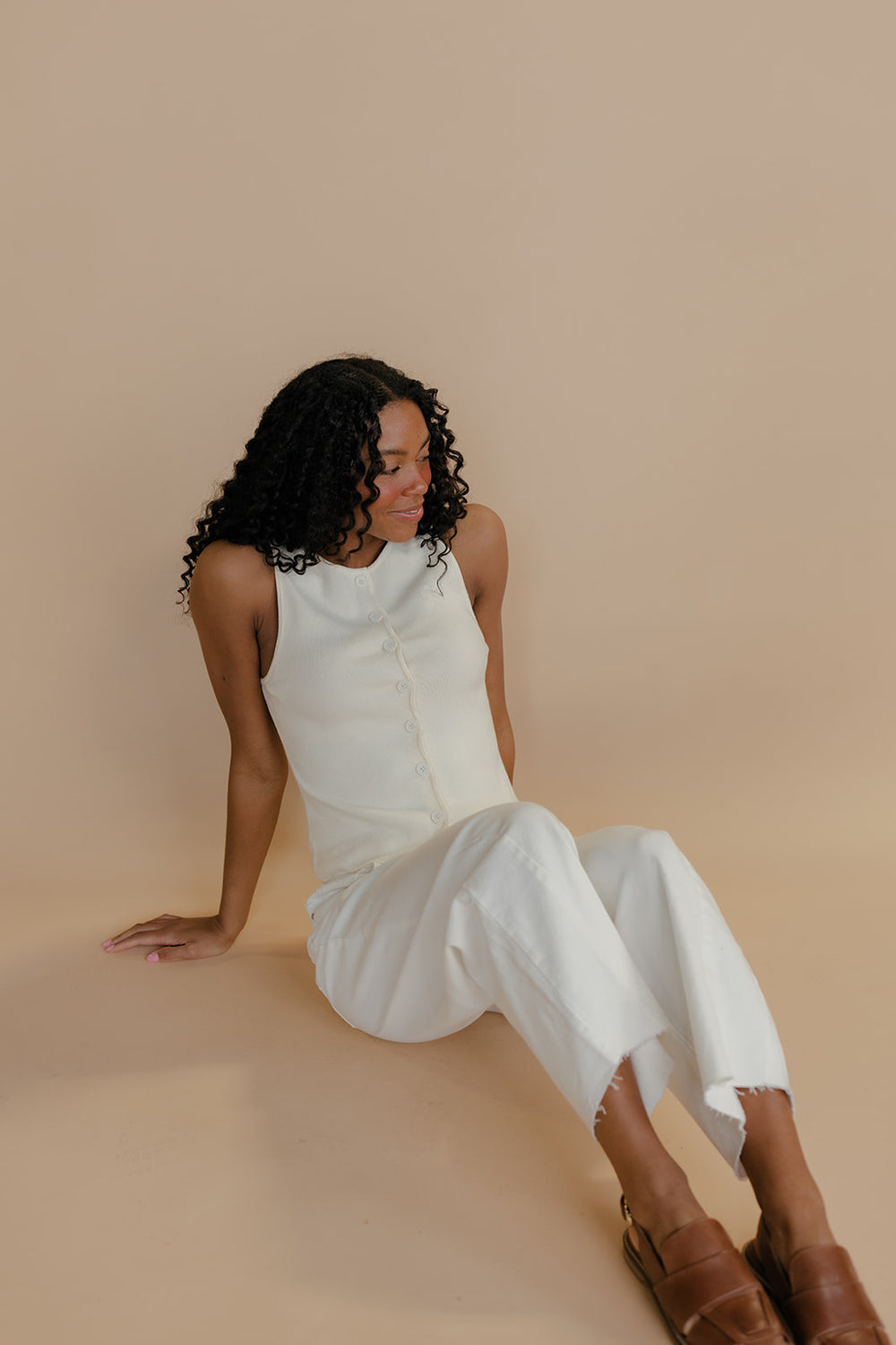 Woman in a white dress sitting on a beige background