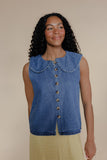 Woman wearing a blue denim vest with a beige background