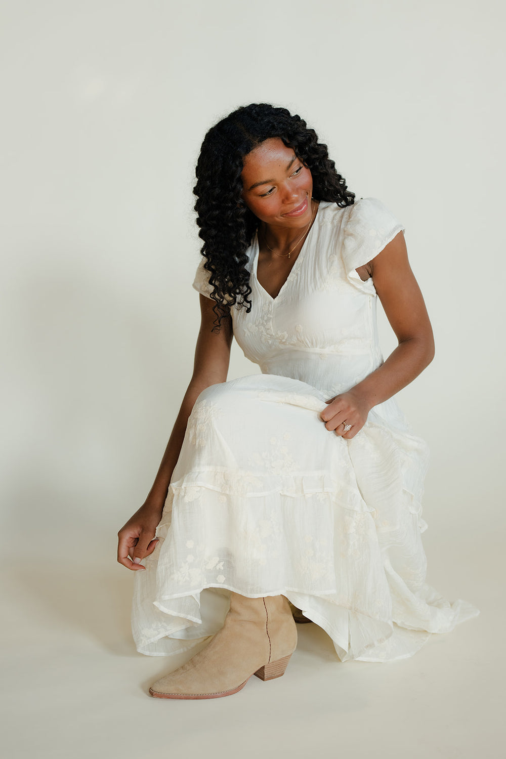 Woman in a white dress sitting on a white background