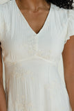 Close-up of a person wearing a white dress with a subtle pattern.
