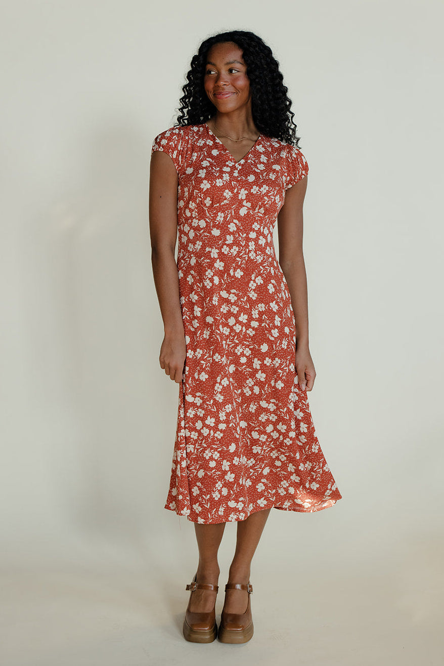 Woman wearing a red floral dress against a plain background
