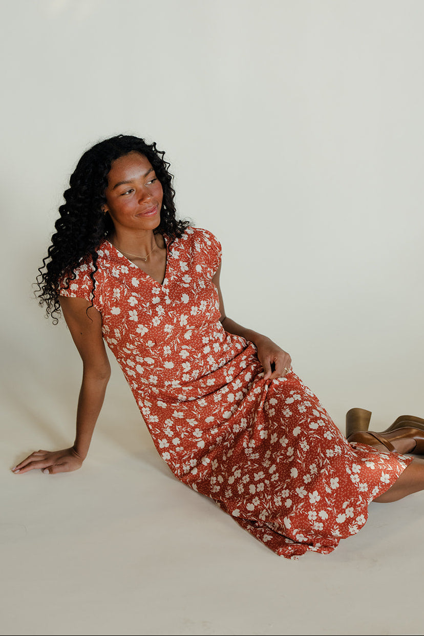 Woman in a red floral dress sitting on a white background
