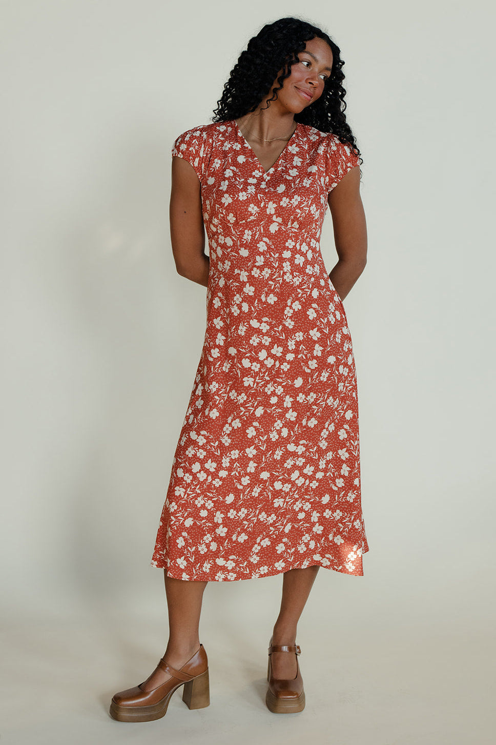 Woman wearing a red floral dress against a plain background
