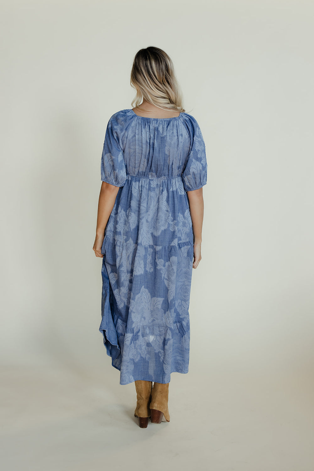 Woman wearing a blue patterned dress against a plain background