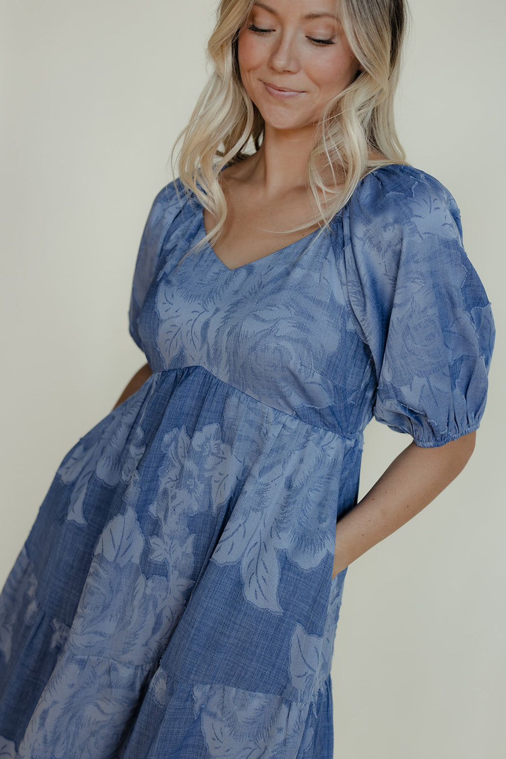 Woman wearing a blue floral dress against a plain background
