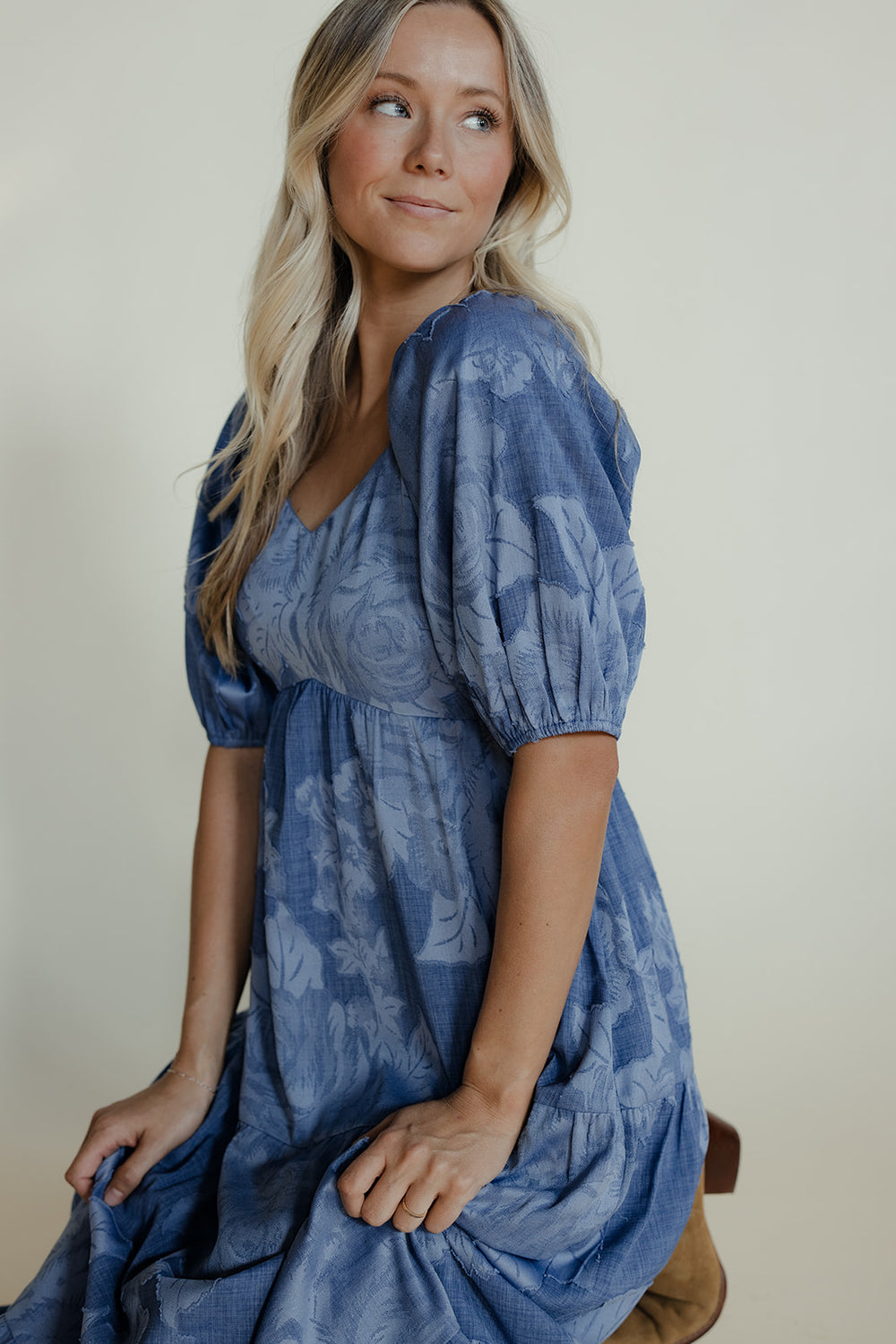 Woman wearing a blue dress with puff sleeves against a plain background