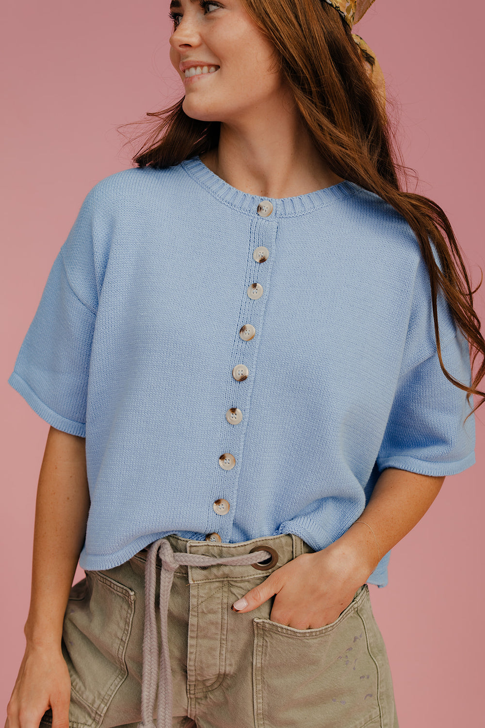 Woman wearing a blue button-up shirt against a pink background