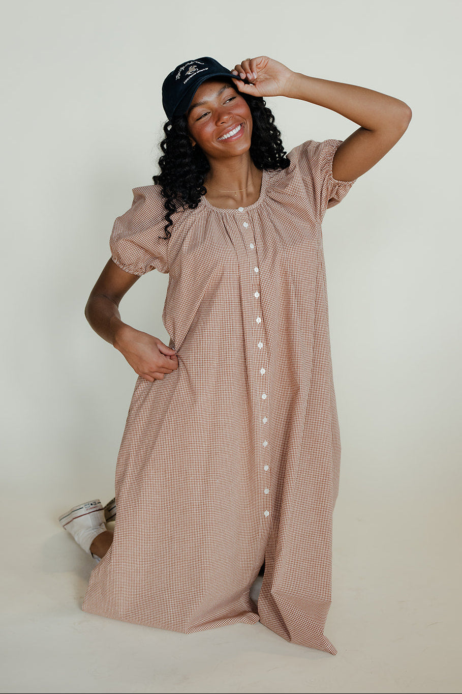 Woman wearing a long beige dress with short sleeves against a plain background