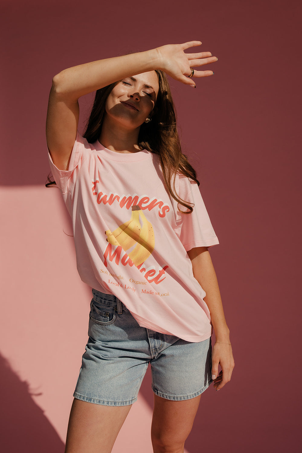 Woman wearing a pink t-shirt with text and graphics against a pink background