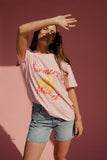 Woman wearing a pink t-shirt with text and graphics against a pink background