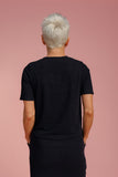 Person wearing a black t-shirt against a pink background