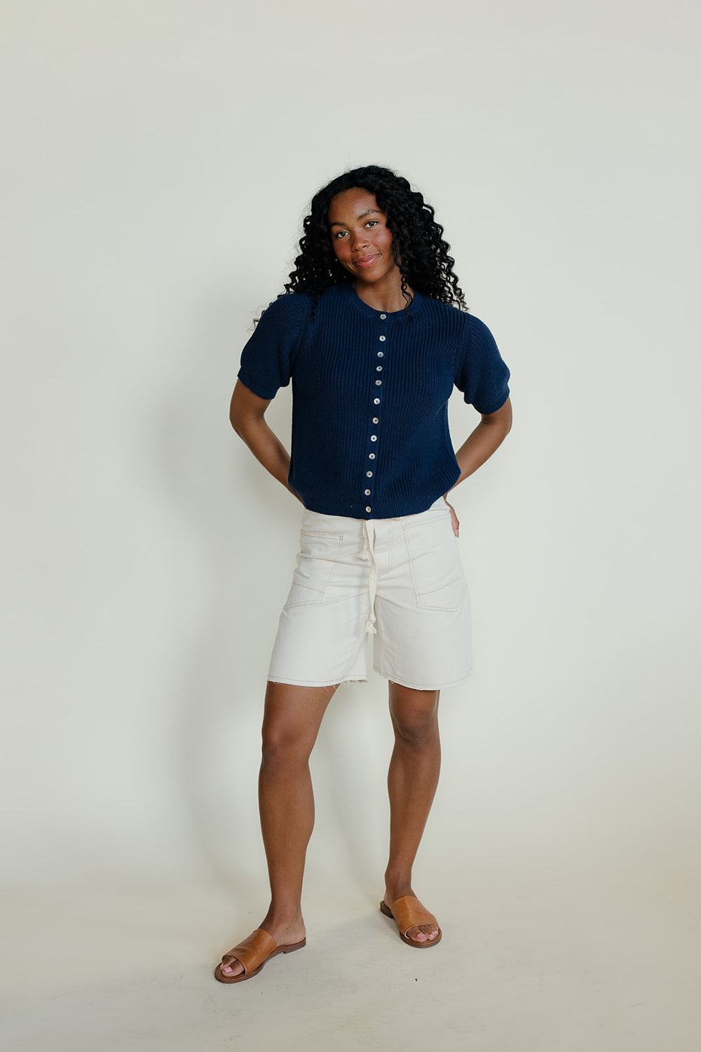 Woman wearing a navy blue shirt and white shorts on a plain background