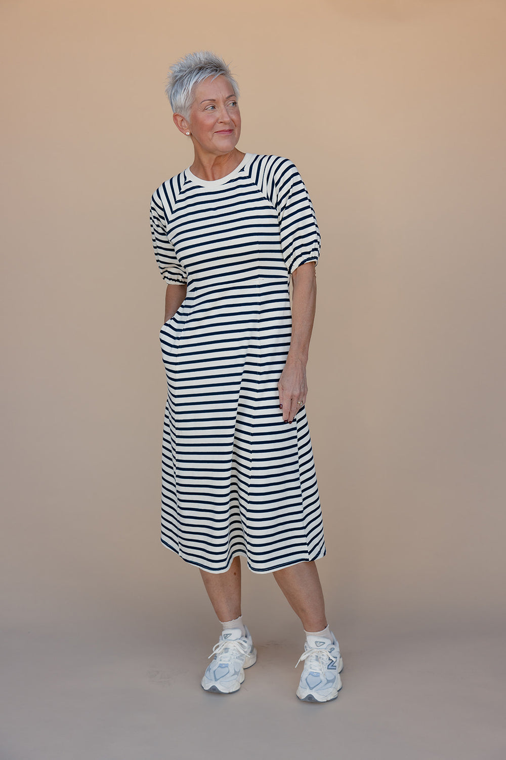 Woman wearing a black and white striped dress against a beige background