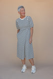 Woman wearing a black and white striped dress against a beige background