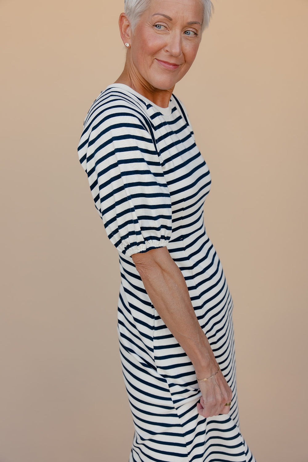Woman wearing a striped dress against a beige background