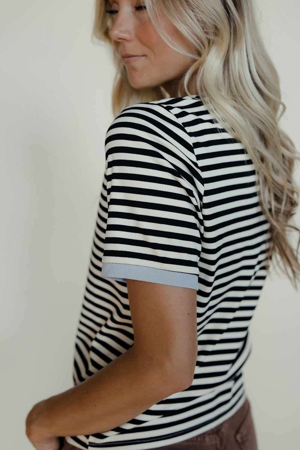 Woman wearing a black and white striped shirt against a plain background