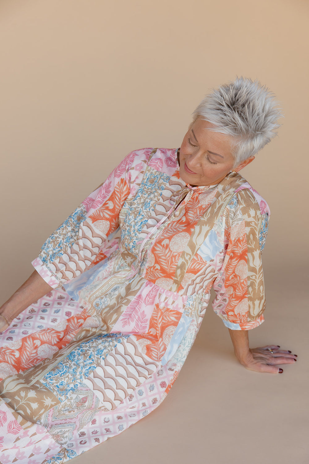 Woman wearing a colorful floral dress on a beige background