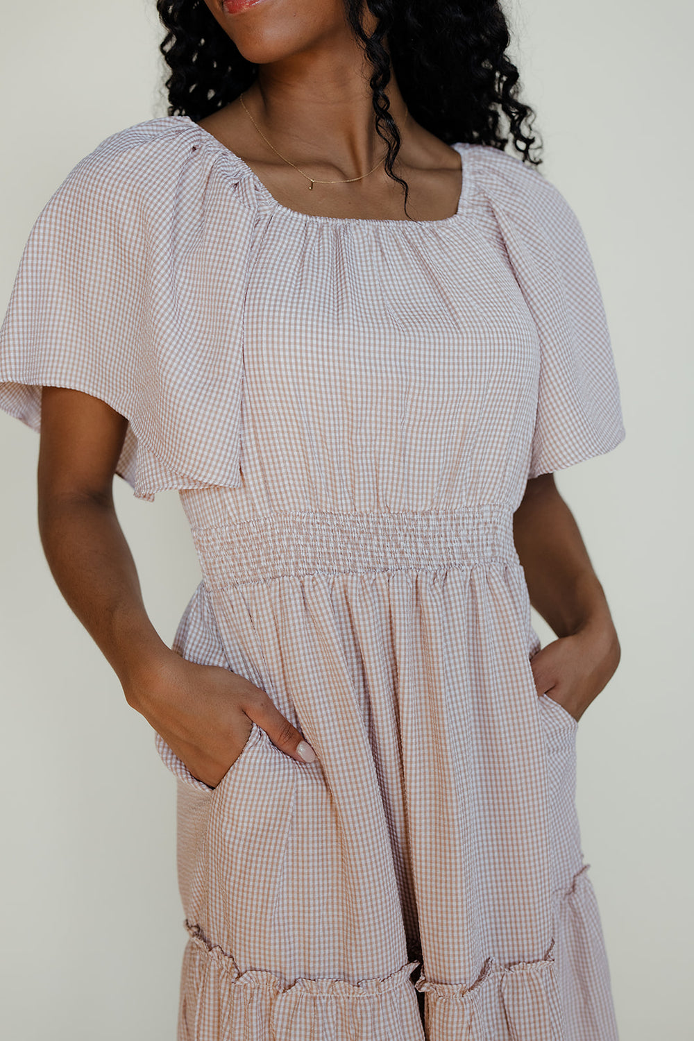 Woman wearing a checkered dress with a plain background