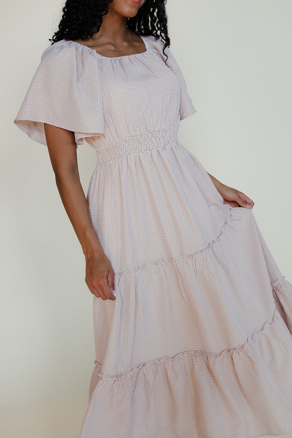 Woman wearing a light purple dress with ruffled sleeves against a white background
