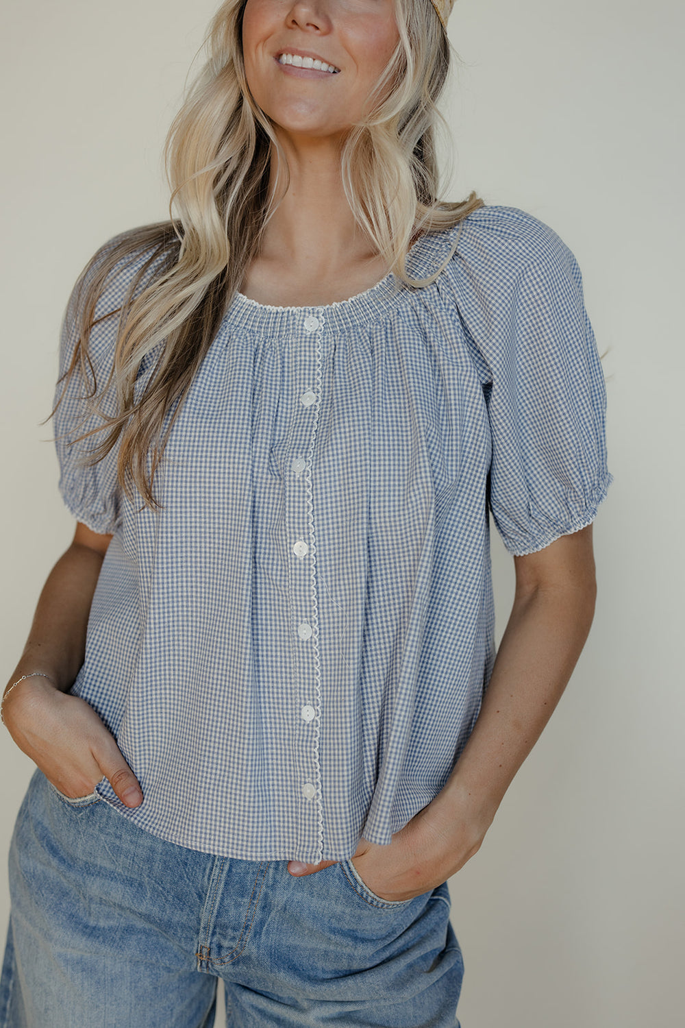 Woman wearing a blue checkered blouse with short sleeves against a plain background