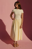 Woman in a yellow dress standing against a pink background